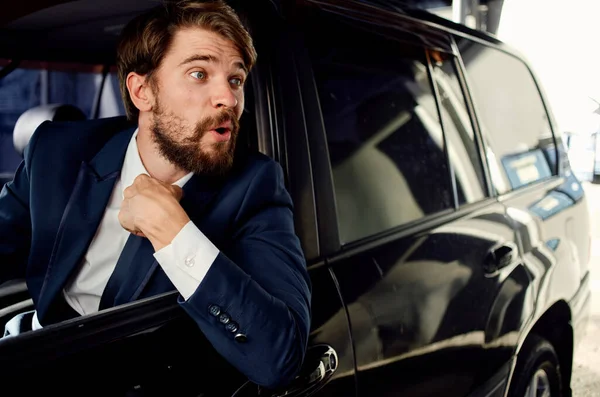 Hombre feliz en traje mira por la ventana del coche y gestos con las manos — Foto de Stock