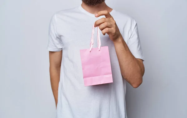 Modelo homem com saco de presente na mão em feriados fundo luz — Fotografia de Stock