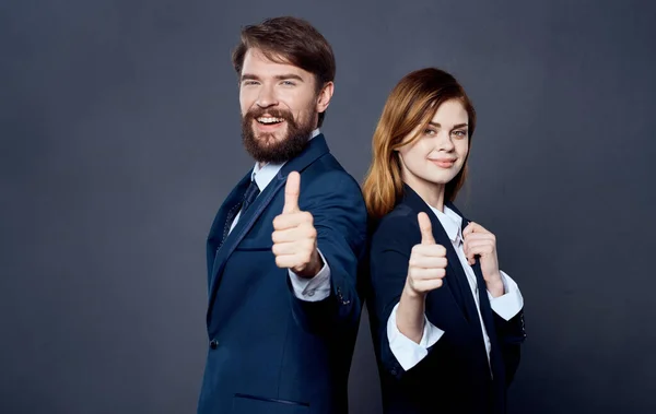 Business successful people in suits stand with their backs to each other on a gray background confident look