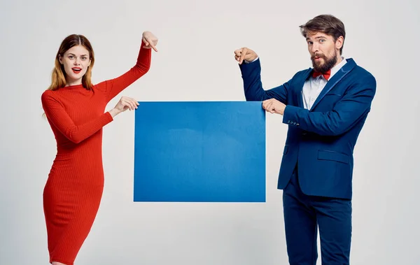 Man and woman with blue sheet of paper on a light background cropped view