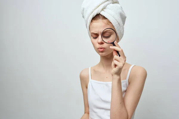 Mujer con lupa en la mano y acné en la cara con una toalla en la cabeza acné — Foto de Stock