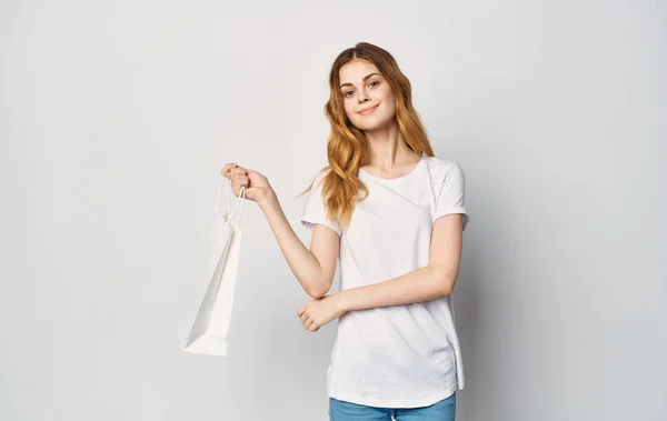 Woman in white t-shirt with package in hand shopping isolated background — Stock Photo, Image