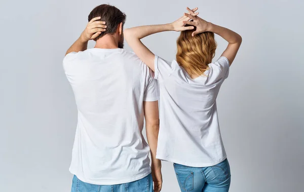 Un uomo e una donna con le stesse magliette e gli stessi jeans stanno gesticolando con le mani, retrovisore — Foto Stock