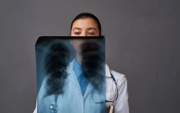 Lékař v lékařských šatech s rentgenem na šedém pozadí výzkumu v laboratoři — Stock fotografie