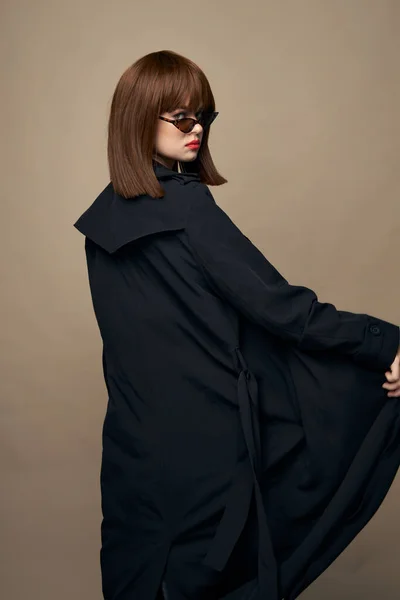 Modelo atraente casaco preto maquiagem brilhante posando em um fundo isolado — Fotografia de Stock