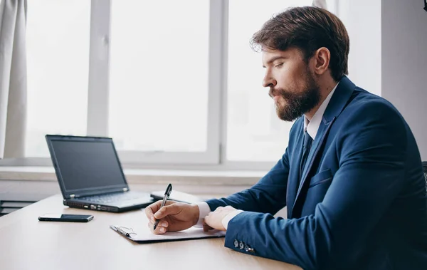 Man in the office at the table documents laptop mobile phone window office