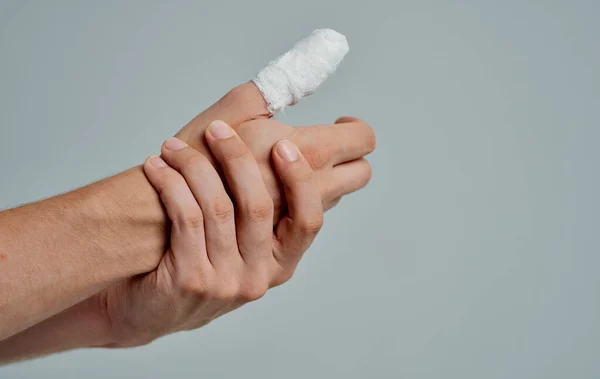 Чоловік у білій футболці зламаний палець, перев'язаний ліками — стокове фото