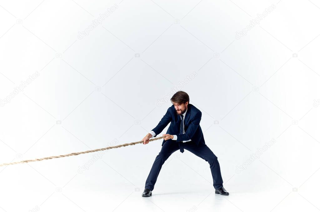 business man with a rope in his hands on a light background tension model of achieving the goal