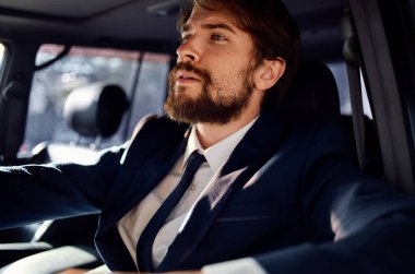 Takım elbise içinde araba süren başarılı bir genç adam.