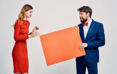 Model ve duygusal bir kadınla enerjik bir adam arka planda şov dünyasında reklam yapıyor.
