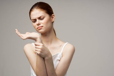 Elleri hafif arka planda, beyaz tişörtlü bir kadın el kol hareketi yapıyordu.