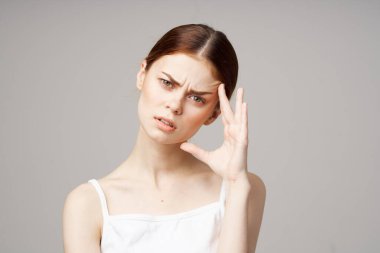 Beyaz tişörtlü baş ağrısı kadın elleriyle yüzüne dokunuyor sağlık sorunları.