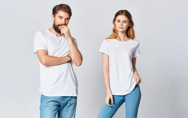 Un uomo e una donna in jeans e una t-shirt su uno sfondo chiaro gesticolando con le mani ritratto amici famiglia — Foto Stock