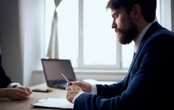 Man in the office at the table documents laptop mobile phone window office