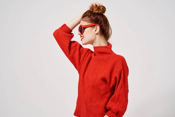빨간 스웨터를 입고 양손으로 선글라스를 끼고 있는 유행하는 여성 모델 — 스톡 사진