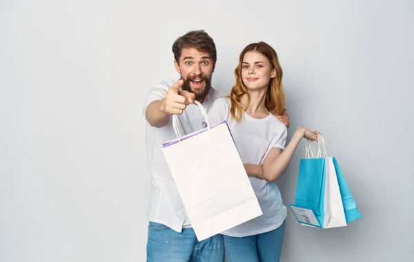 Giovane coppia in bianco T-shirt con pacchetti in mano shopping gioia — Foto Stock