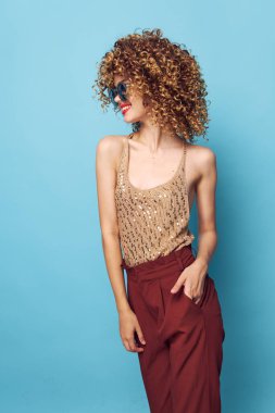 Kıvırcık saçlı, kırmızı dudaklı, şık, çıplak omuzlu bir kadın portresi. 