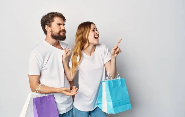 Mladý pár v bílých tričkách s balíčky v rukou nakupování radost — Stock fotografie