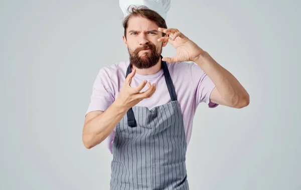 The cook in a gray mess and in a pink shirt is gesturing with his hands of emotion — Stock Photo, Image
