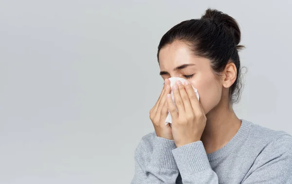 Mujer sopla su nariz en una servilleta secreción nasal problemas de salud fondo gris — Foto de Stock