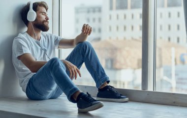 Pencerenin yanında oturan sevimli adamlar kulaklık takıp müzik dinliyorlar.