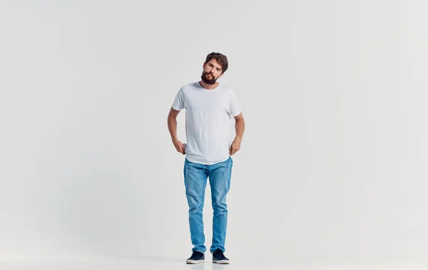 Uomo in bianco t-shirt e jeans emozioni movimento studio stile di vita isolato sfondo — Foto Stock
