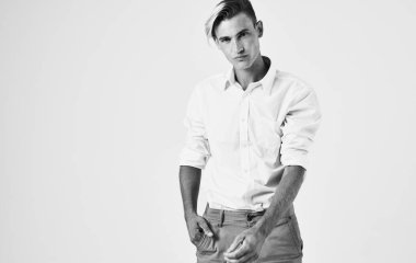 Tişörtlü ve pantolonlu yakışıklı bir adam arka planda elleri açık bir şekilde el kol hareketi yapıyor.