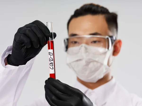 Male laboratory assistant protective mask blood test black gloves gray background