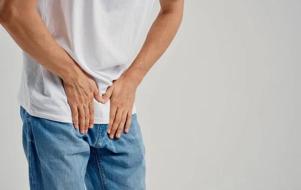 Hombre experimentando dolor debajo del cinturón en la ingle y jeans modelo camiseta — Foto de Stock