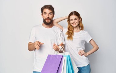 Beyaz tişörtlü mutlu genç çift ellerinde paketlerle alışveriş yapmak çok keyifli.