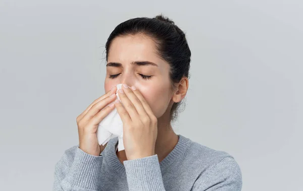 Mujer sopla su nariz en una servilleta secreción nasal problemas de salud fondo gris — Foto de Stock