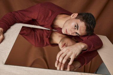 Yakışıklı adam masa yansıması kumaş arka planında cama uzanıyor.