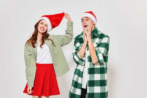 Чоловік у сорочці та жінка у різдвяному капелюсі на світлому фоні — стокове фото