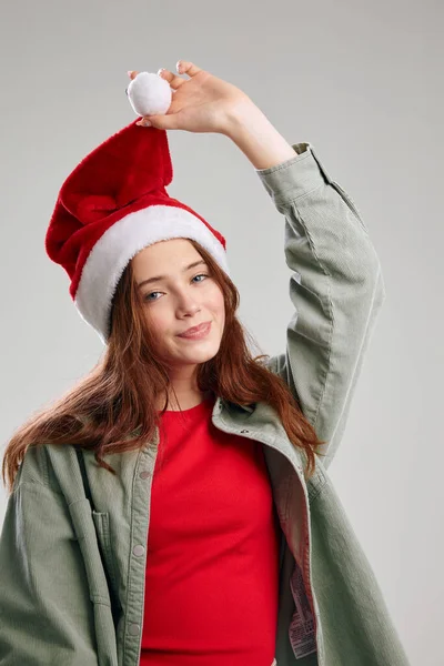 Χαριτωμένο κοριτσάκι σε ένα καπέλο με ένα pom-pom σε ένα γκρίζο φόντο κόμμα Χριστούγεννα το νέο έτος — Φωτογραφία Αρχείου