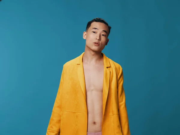 Handsome guy in a yellow jacket on a naked torso and blue background — Stock Photo, Image