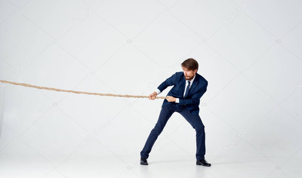 business man with a rope in his hands on a light background tension model of achieving the goal