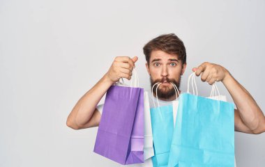 Beyaz tişörtlü sakallı bir adam. Paketleri elinde. Tatil tatili tabelası.