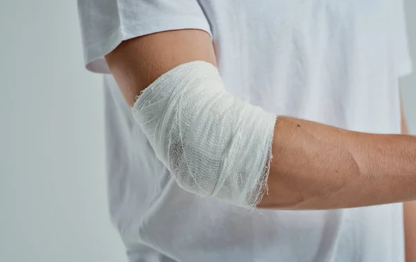 Hombre con el brazo vendado codo y el dedo medicina lesión —  Fotos de Stock