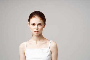 Beyaz tişörtlü kadın duyguları çıplak omuz sağlık sorunlarını modelliyor.