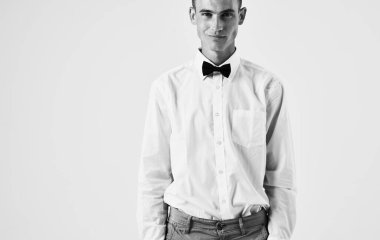 Açık arkaplan portresi üzerinde gömlek ve papyon takan yakışıklı bir adam.