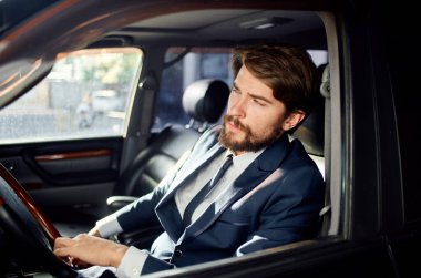 Takım elbiseli yakışıklı bir adam araba kullanıyor. Resmi yaşam tarzı.