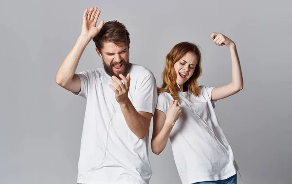 Χαρούμενος άντρας και γυναίκα με ακουστικά ακούνε μουσική και χορεύουν σε γκρι φόντο — Φωτογραφία Αρχείου