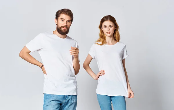 Un uomo e una donna in jeans e una t-shirt su uno sfondo chiaro gesticolando con le mani ritratto amici famiglia — Foto Stock
