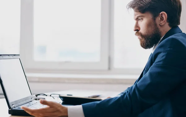 Uomo d'affari seduto a un tavolo in giacca e cravatta davanti a un computer portatile emozioni office manager — Foto Stock