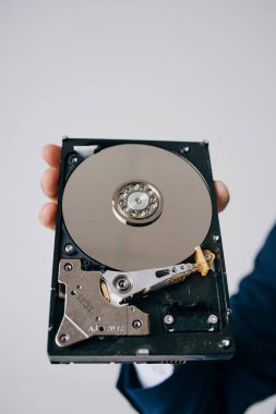 Hard disk, gri bir arka planda bir adamın elinde parçalara ayrıldı.