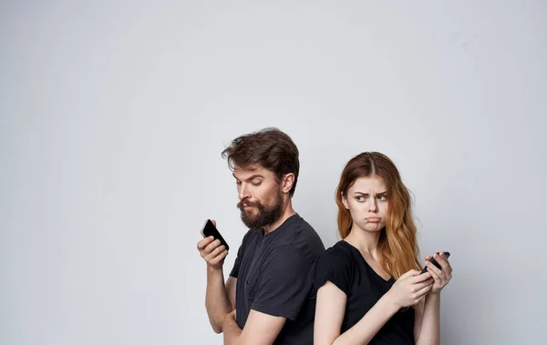 Young couple in black t-shirts with phones in hands communication internet technology — Stock Photo, Image