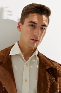Beyaz gömlekli ve kahverengi ceketli yakışıklı bir adamın portresi.