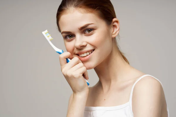 Mulher em branco t-shirt escova de dentes sorriso saúde e higiene — Fotografia de Stock