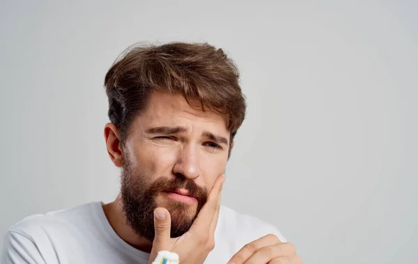 Ένας άνθρωπος με μια οδοντόβουρτσα χειρονομίες με τα χέρια του πόνο στην στοματική κοιλότητα πρωινές διαδικασίες — Φωτογραφία Αρχείου