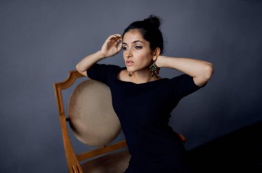 Küpeli seksi bir kadın portresi ve yakın çekimde siyah bir elbise.